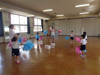 リズム室でポンポンを持って踊る4歳児