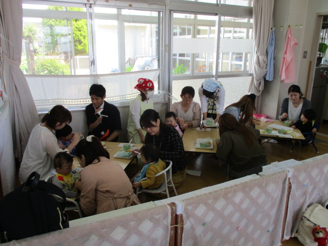 保育参観で離乳食をおうちの人たちに食べさせてもらっている0歳児