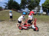 5歳児に、乗っている三輪車を押してもらう4歳児