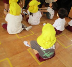 床の四角い枠に合わせて座る3歳児
