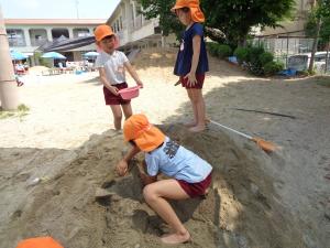 砂場でトンネルづくりをする5歳児