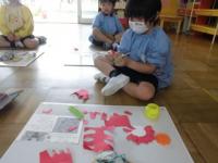 4歳児へのプレゼントの花を赤色の色画用紙で作る年長男児