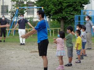 前に出て校長先生とラジオ体操をする小学生