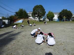 先生と一緒に草ぬきをする卓球部の中学生