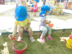 2歳児が砂遊びをして楽しんでいる様子