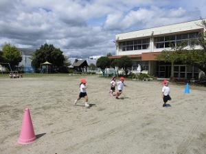 園庭でかけっこをする4歳児