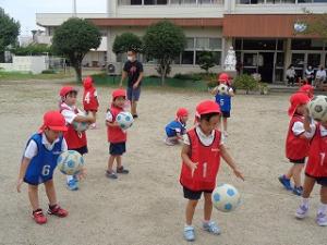 サッカーボールを地面についてみる4歳児