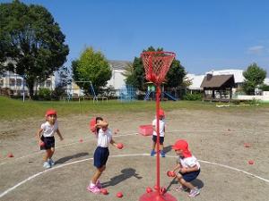 赤の玉入れをする4歳児