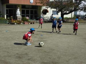 サッカーゲームでボールを追いかける5歳児