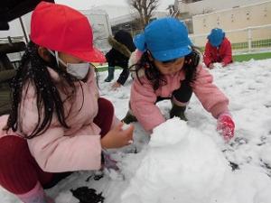 雪だるまづくりをしている園児