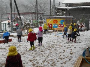 中庭で雪遊びをする3歳児