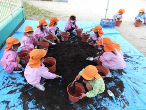 土を植木鉢に入れる子ども
