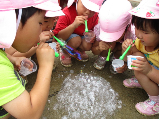 地面にシャボン玉を吹きかける4歳児