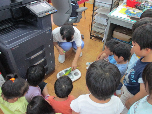 事務所でキュウリの重さを量る子ども達
