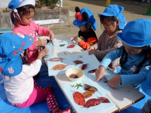 3歳児　落ち葉で遊んでいます。