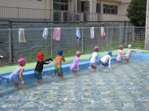 背中に水をかけあっている5歳児