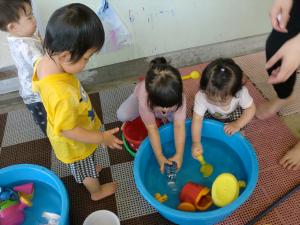 1歳児　タライの水で遊んでいる