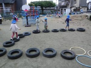 4歳児が並べたタイヤの上を渡って遊んでいます。