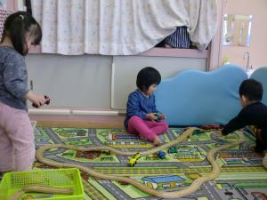 1歳児が線路を長くつなげ、列車を走らせて遊んでいます。