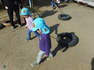 2歳児が友達と一緒にタイヤ引き遊びを楽しんでいます。