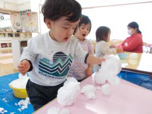 1歳児が雪をまるめています