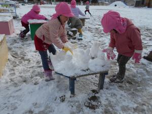 友達と一緒に雪だるまをつくる3歳児