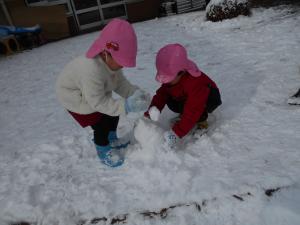 園庭で雪遊びをする3歳児の男の子たち