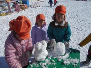 友達と雪だるまをつくっている子ども達