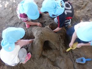 3歳児が砂山をつくってトンネルを掘っています。