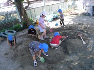 5歳児が砂場で川をつくっています。