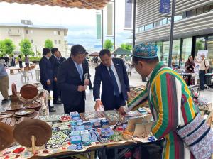 仲川市長がアブドゥラフモノフ駐日ウズベキスタン大使 からをサマルカンドの工芸品について説明を受ける様子