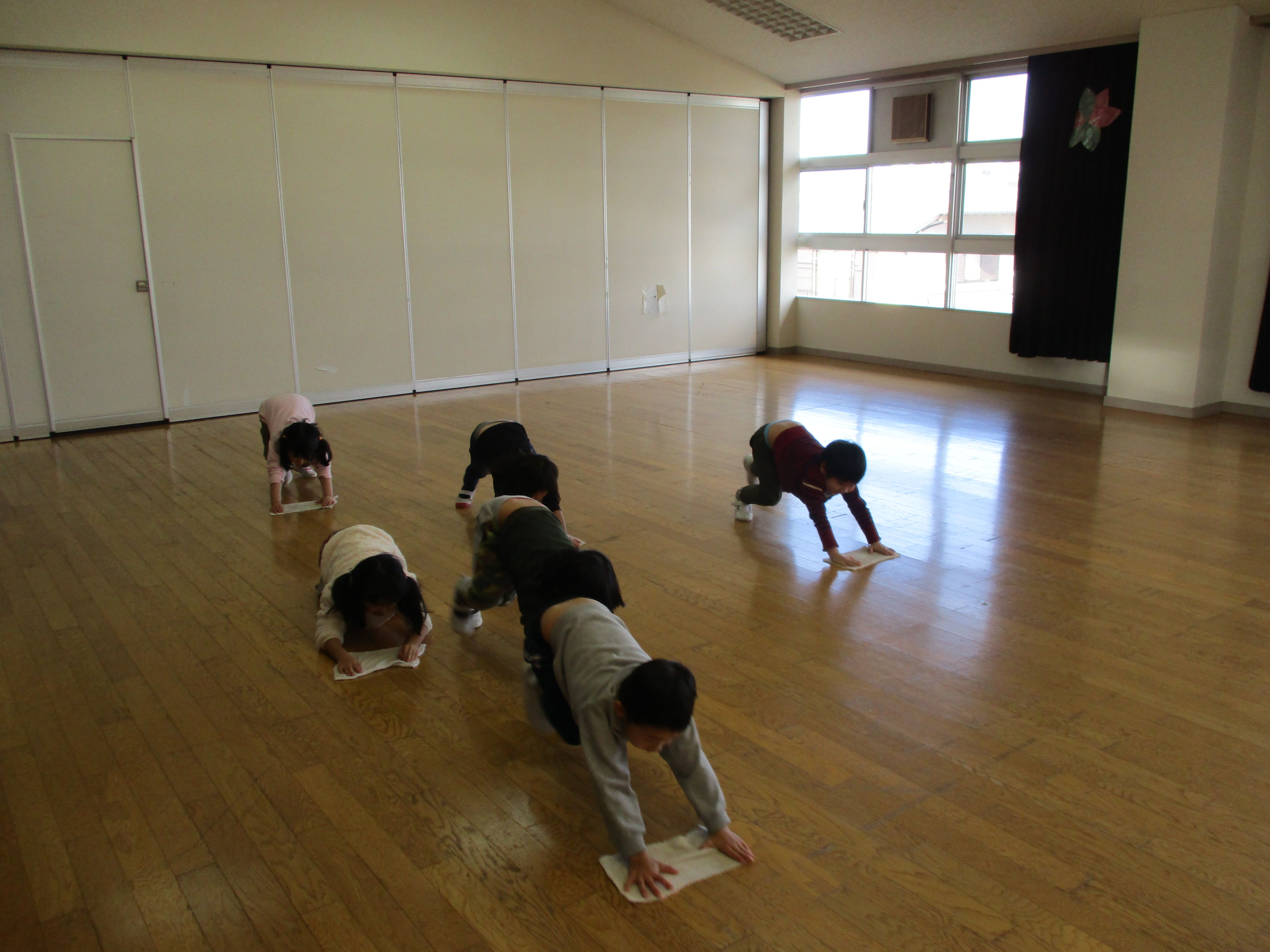 ぽっぽるーむの床を拭く5歳児
