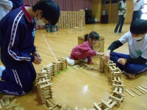 3歳児がお兄さん先生と一緒にカプラを積んでいます