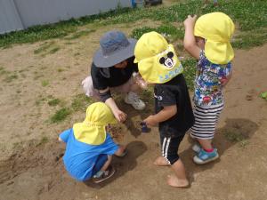 子どもが保育士と一緒に泥遊びをしています。