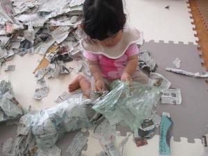 破いた新聞紙を袋に詰めている子ども