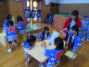お寿司屋さんを楽しんでいる5歳児