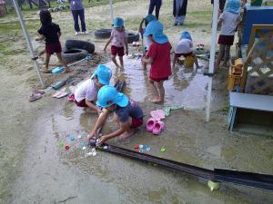 砂場で水遊びをしている4歳児