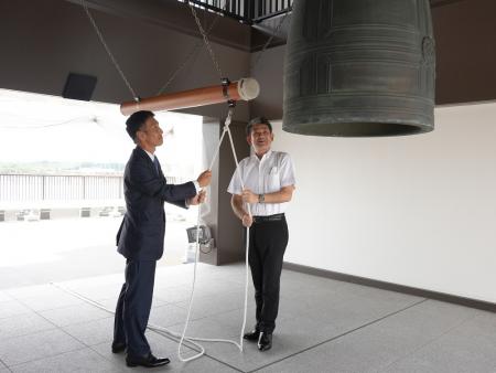 市長と上田社長が鐘を打つ様子