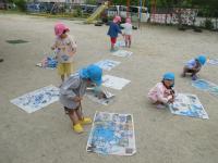 園庭で新聞紙に絵の具をポタポタたらしています