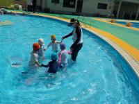 3歳児先生と水の中で子どもで輪になっています