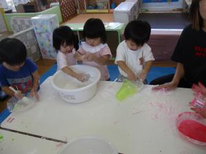 色のついた片栗粉を触っている子ども達1
