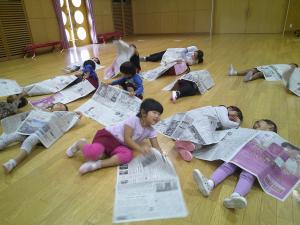 新聞紙を使って遊んでいる4歳児