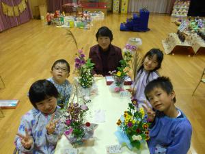 きれいにできた生け花と写真を撮る子ども達