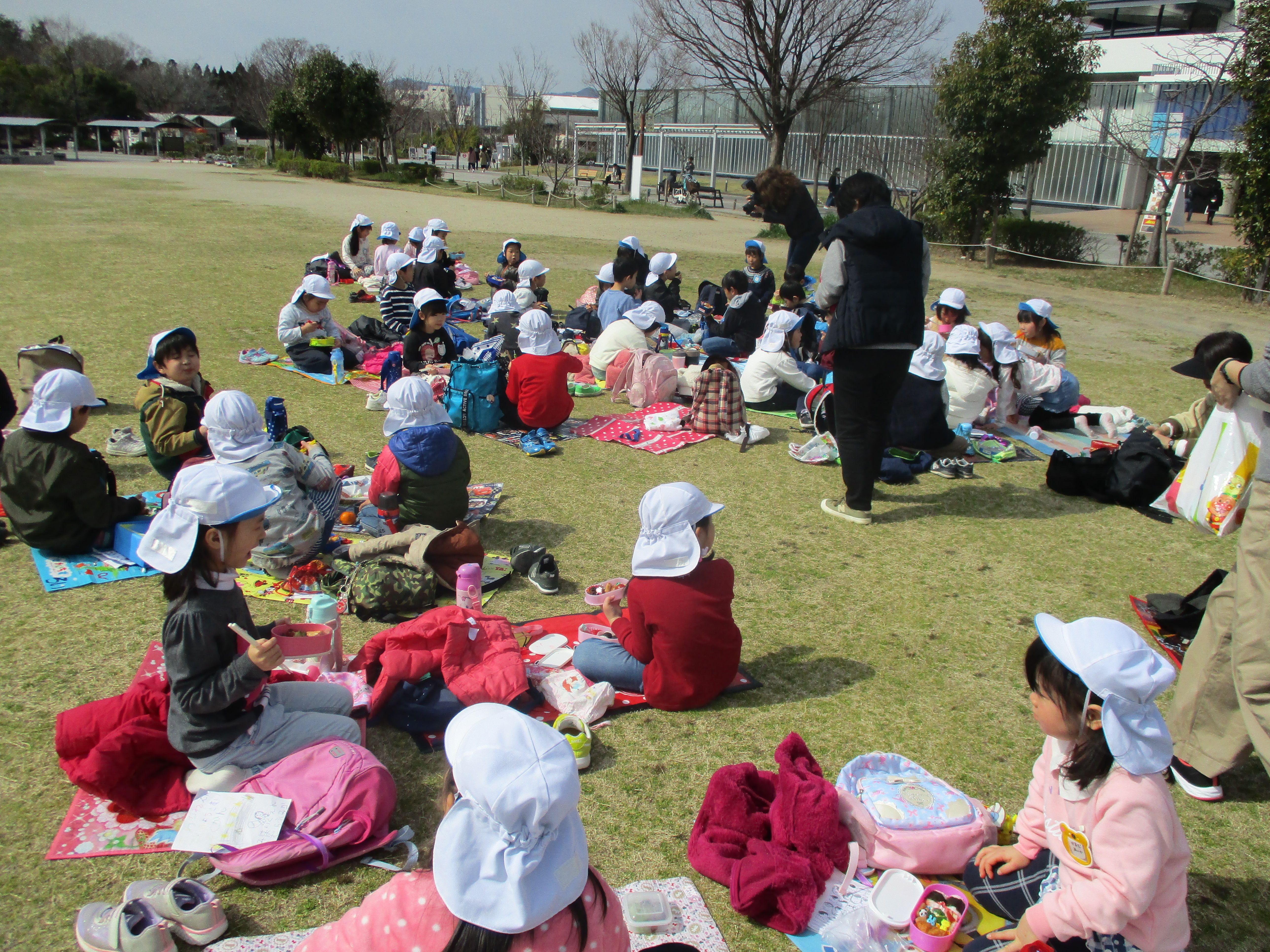 広場でお弁当を食べる子どもたち
