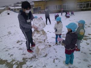 4歳児が大きな雪だるまをつくっています