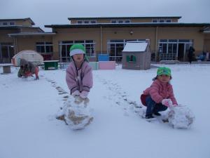 3歳児が園庭で雪の玉をつくっています