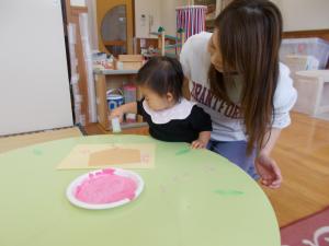 ピンクの絵の具を付けてお花のスタンプをしています