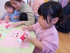 だるまの顔を糊で貼っています