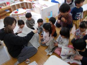 1歳児新聞を丸めています