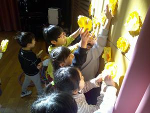 4歳児がみんなで仲良く手づくりの花を飾っています